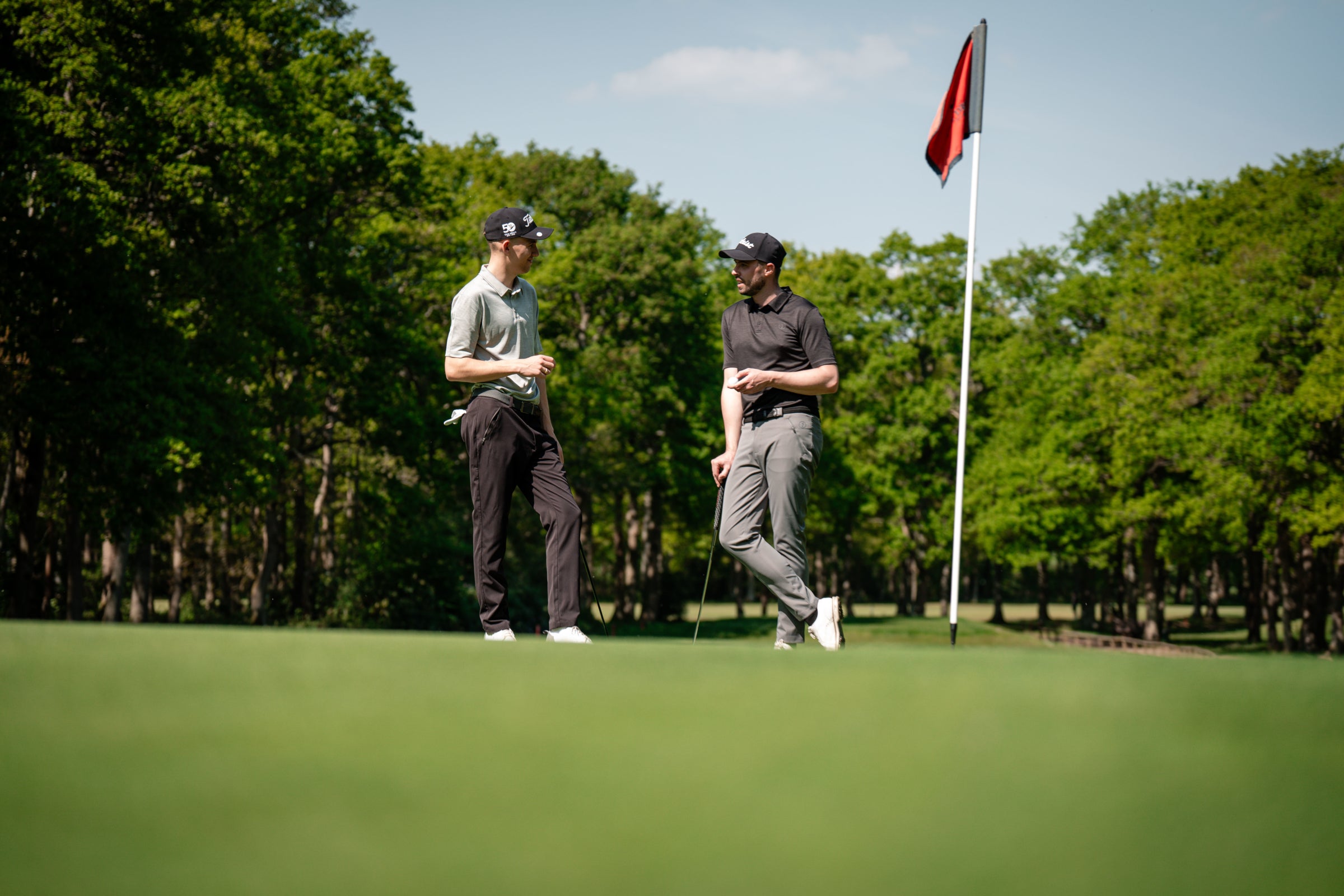Two golfers on a green course with trees