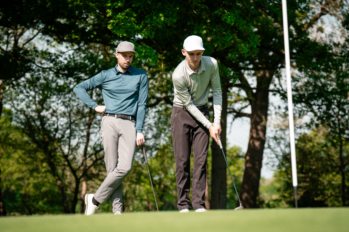 Two golfers on green lining up a putt