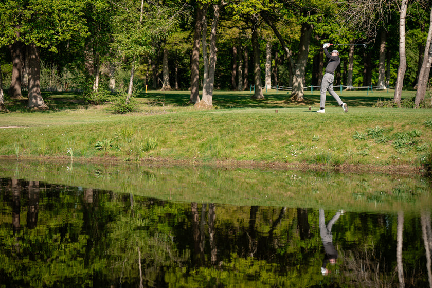 Golfer teeing off by a pond