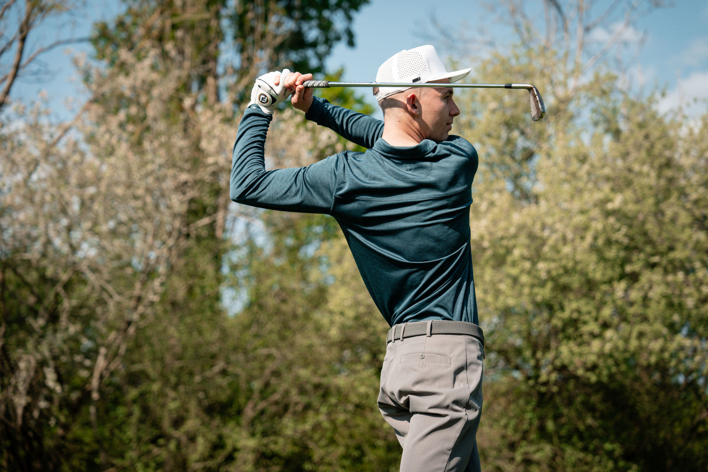 Golfer in long-sleeve top swinging a club on the course
