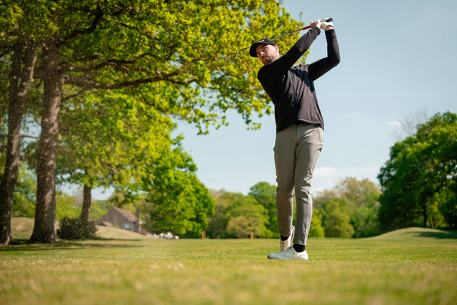 Golfer pitching in grey golf trousers